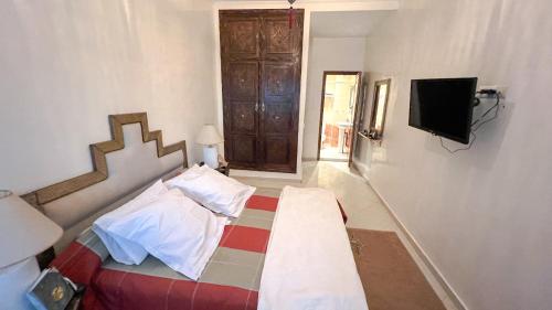 - une chambre avec un lit et une télévision murale dans l'établissement Flair's Family Apartment, à Marrakech