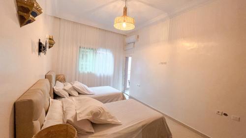 een kamer met 2 bedden en een kroonluchter bij Flair's Family Apartment in Marrakesh