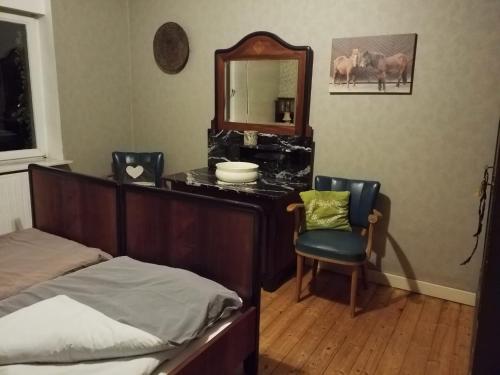 ein Schlafzimmer mit einem Bett, einem Spiegel und einem Stuhl in der Unterkunft Staffel`s Hob in Oberrosphe