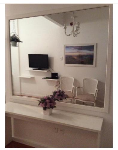 um espelho que reflecte uma sala de estar com uma televisão e cadeiras em Lindo Studio Ipanema no Rio de Janeiro