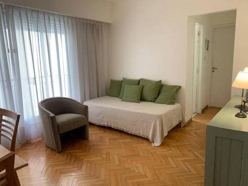 Un dormitorio con una cama con almohadas verdes y una silla en Cálido departamento en Palermo en Buenos Aires