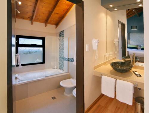 a bathroom with a sink and a tub and a toilet at Melodias Posada Boutique in Los Reartes