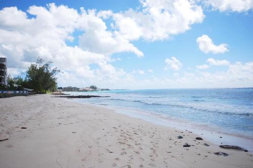 a beach with footprints in the sand and the ocean at Margate Gardens 4 by Blue Sky Luxury in Bridgetown