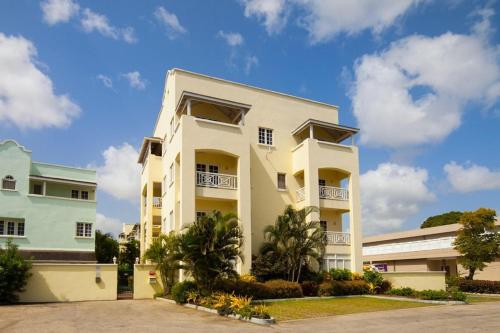 un edificio bianco con palme di fronte di Margate Gardens 4 by Blue Sky Luxury a Bridgetown