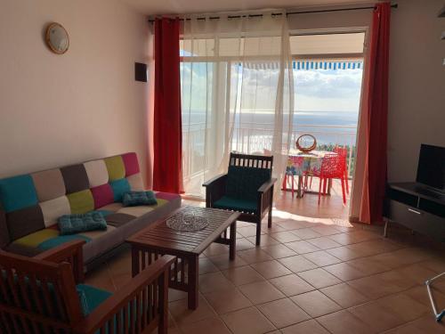 a living room with a couch and a table at PARADIS AU SOLEIL, vue panoramique sur mer in Bouillante