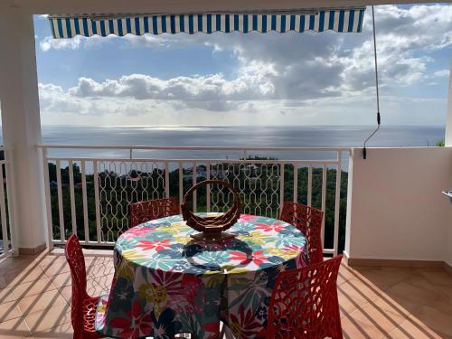 a table on a balcony with a view of the ocean at PARADIS AU SOLEIL, vue panoramique sur mer in Bouillante
