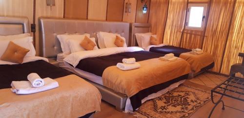 1 dormitorio con 2 camas y toallas. en Sables Chaud Camp, en Adrouine