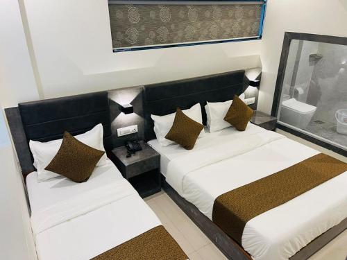 two beds in a hotel room with white and brown pillows at Hotel lime wood in Mumbai