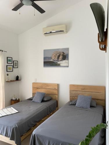 two beds in a room with white walls at El Chante Surf House in Santa Teresa Beach