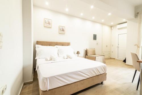 a white bedroom with a large bed and a chair at Elegant Suite 2 near the Beach in Ayía Marína