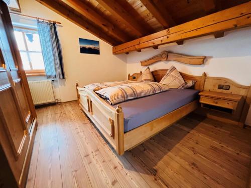 1 dormitorio con cama de madera y suelo de madera en Haus am Dürrach, en Reit im Winkl