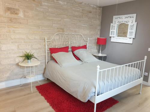 a bedroom with a white bed with red pillows at Le Gîte Senlisien in Senlis