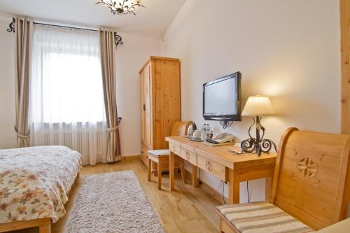 a bedroom with a desk with a television and a bed at Willa Kominiarski Wierch in Zakopane