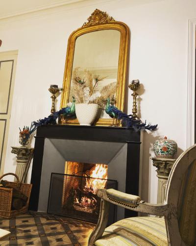a fireplace in a living room with a mirror and a chair at Maison 1823 - Suites de charme à Garons in Garons