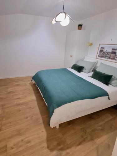 a white bedroom with a large bed with green pillows at Victoire émeraude 301 hôtel de ville in Saint-Dizier