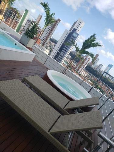 un balcón con 2 sillas y una piscina en un edificio en Manaíra Apart Hotel 1406, en João Pessoa