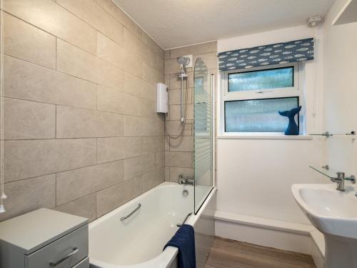 a bathroom with a bath tub and a sink and a window at Shorelands in Wadebridge