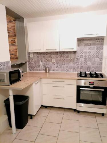 a kitchen with white cabinets and a stove at Le temps d'une pause in Lillers