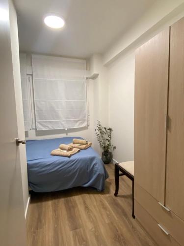 1 dormitorio con cama con sábanas azules y ventana en Bonito piso cerca de Ventas, Madrid, en Madrid