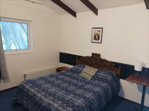 a bedroom with a bed with a blue comforter and a window at Hotel Estación Náutica - Aeropuerto in Punta Arenas