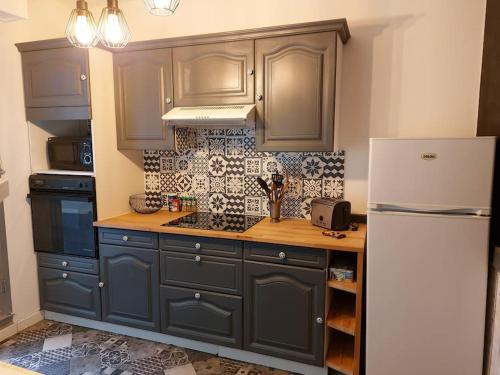 a kitchen with blue cabinets and a white refrigerator at Appart hyper centre- Parking in Vierzon