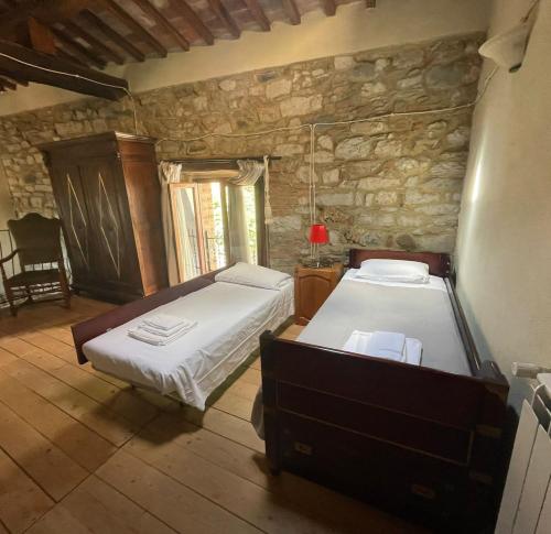 1 dormitorio con 2 camas y pared de piedra en Il Fiore di Montieri, en Montieri