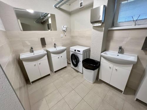 een badkamer met 2 wastafels en een wasmachine bij Hostel H18 in Bardejov