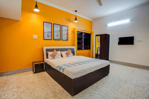 een slaapkamer met een bed en een gele muur bij OYO Home Jaam's Home Stay in Bhubaneshwar