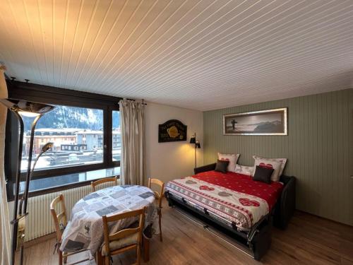 une chambre avec un lit, une table et une fenêtre dans l'établissement STUDIO DENT DU CAIMAN, CHAMONIX hyper CENTRE, PARKING, VUE MONT BLANC, à Chamonix-Mont-Blanc