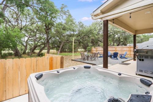 a hot tub in a backyard with a fence at Woodacre Cottage in Wimberley
