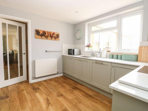 a kitchen with white cabinets and a sink and a window at Fallowfield in Great Yarmouth