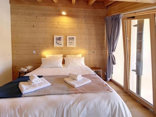 une chambre avec un grand lit avec deux serviettes dessus dans l'établissement Chalet Cachette · Accès direct aux pistes · Wifi gratuit · Parking couvert · Confort moderne - FR-1-344-727, à Saint-Martin-de-Belleville