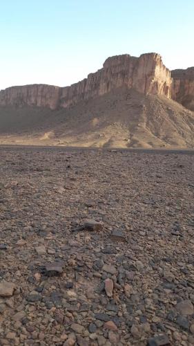 a large rocky area with a mountain in the background at Bivouac Les Nomades & Foum zguid to chegaga tours in Foum Zguid