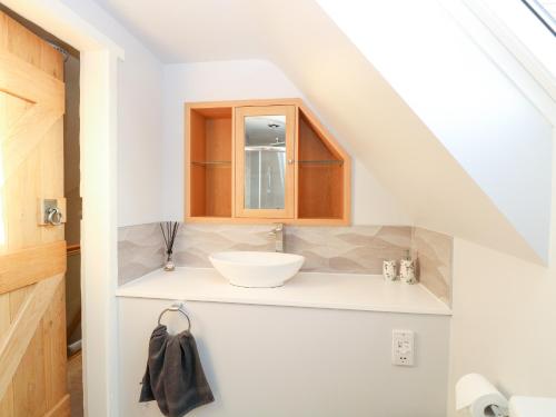 La salle de bains est pourvue d'un lavabo blanc et d'un comptoir. dans l'établissement Hillside Cottage, à Beeston