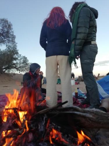 a group of people standing around a fire at Bivouac Les Nomades & Foum zguid to chegaga tours in Foum Zguid