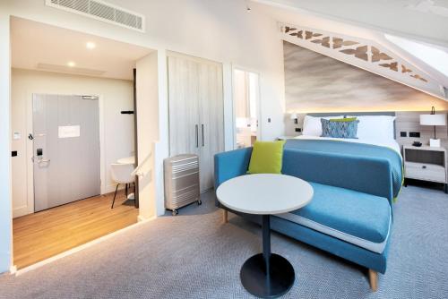 a bedroom with a blue bed and a white table at Staybridge Suites - Dundee by IHG in Dundee