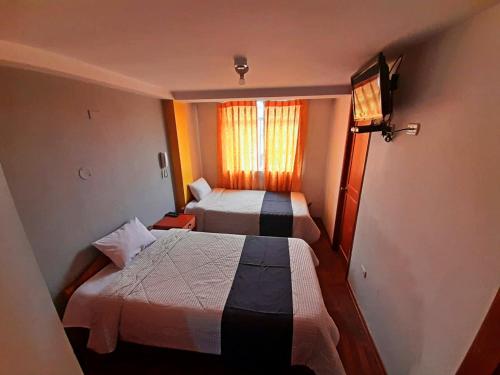 Hotel Wayra Dreams في كوسكو: غرفة صغيرة بسريرين ونافذة