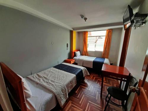 a small bedroom with two beds and a desk and a window at Hotel Wayra Dreams in Cusco