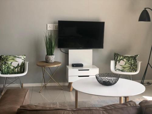 a living room with a tv and two chairs and a table at Urban Awe Apartment: iTowers 21st Floor in Gaborone