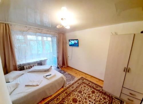 a bedroom with two beds and a tv on the wall at Квартира в центре in Oral