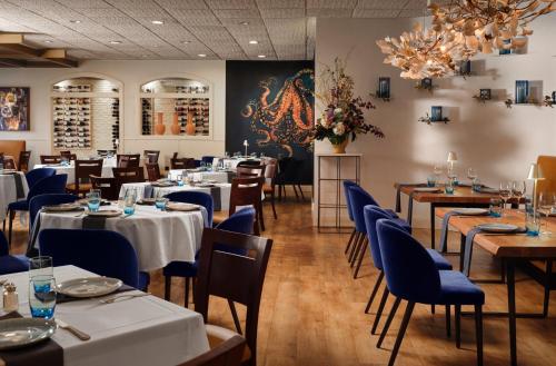 a restaurant with tables and chairs and a chandelier at Holiday Inn & Suites Boston Peabody by IHG in Peabody