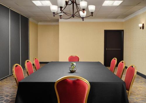 a conference room with a black table and red chairs at Holiday Inn & Suites Boston Peabody by IHG in Peabody