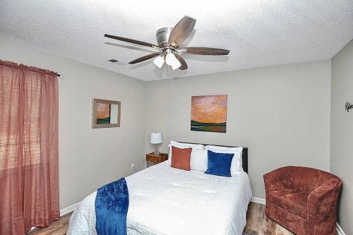 a bedroom with a bed with a ceiling fan and a chair at Majestic Escape in Charlotte