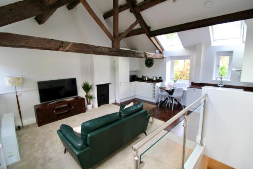a living room with a green couch and a tv at Pheasants Crossing - luxurious and cozy cottage in peaceful rural location in Almondbury