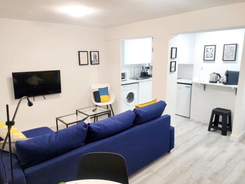 a living room with a blue couch and a kitchen at Acogedor apartamento familiar en área residencial in Madrid