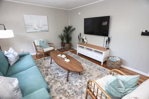 a living room with a couch and a table and a tv at Heart of Galveston Stylish Apt Near Attractions in Galveston
