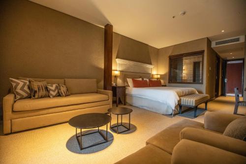 um quarto de hotel com uma cama e um sofá em Pueblo Nativo Resort Golf & Spa em La Cumbre