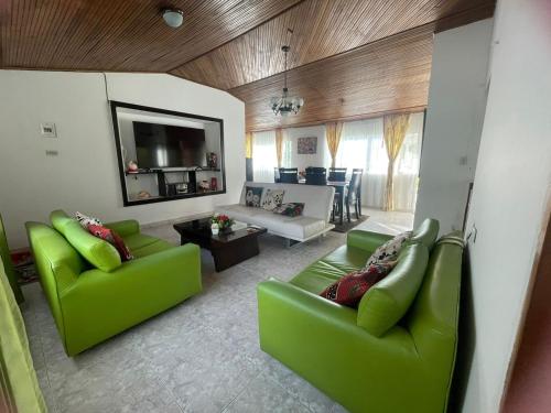 a living room with green couches and a tv at CASA CAMPESTRE VILLA JULIA in Quetame
