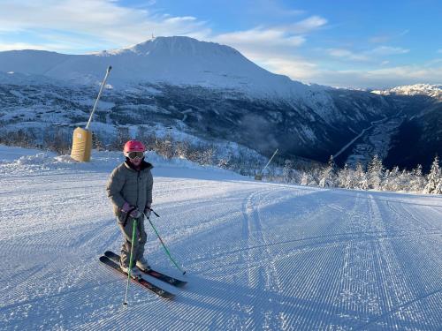 a person is standing on skis in the snow at Astonishing Mountain Lodge at the top of Gaustablikk, 25m2 west facing terrace, 3 bedrooms in Gaustablikk
