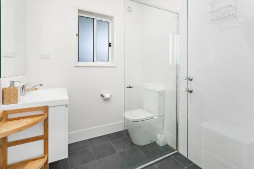 a white bathroom with a toilet and a shower at Sojourne in Shoalhaven Heads
